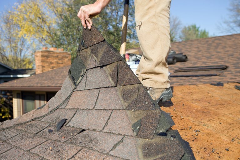 A man installs a shingled roof on a house, showcasing Mr. Max Roofing's expertise in roof replacement.